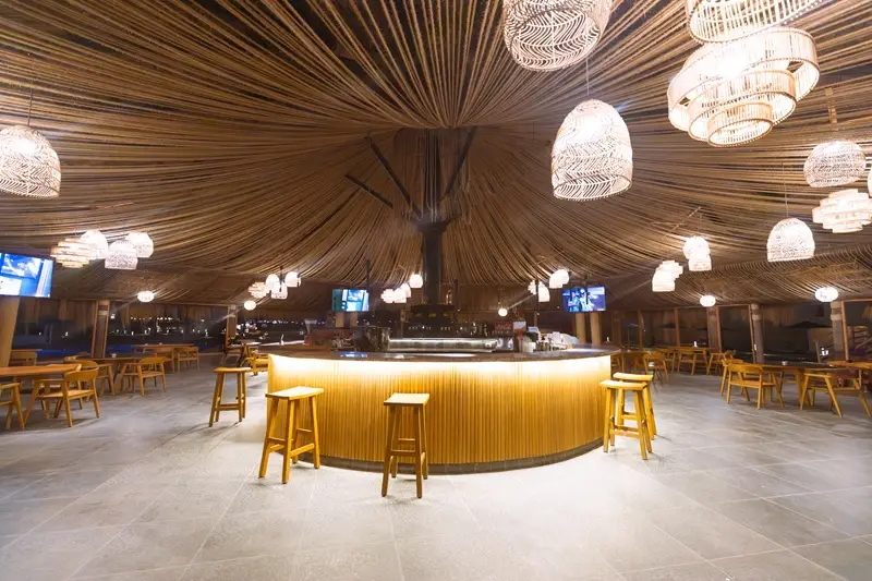 Thatched pool bar at V Grand Sahl Hasheesh surrounded by the swimming pool, with bar stools and wooden seating