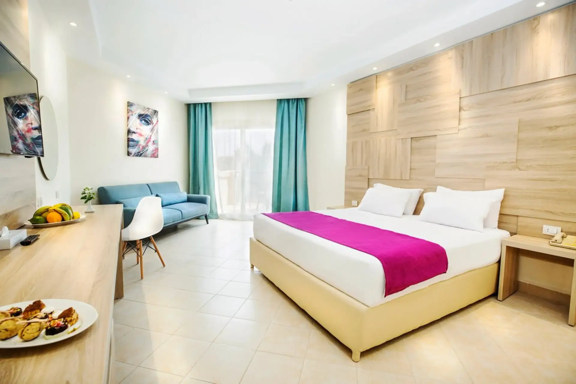 Superior Room at V Grand Sahl Hasheesh with king bed, blue sofa, wood-panelled wall and balcony doors