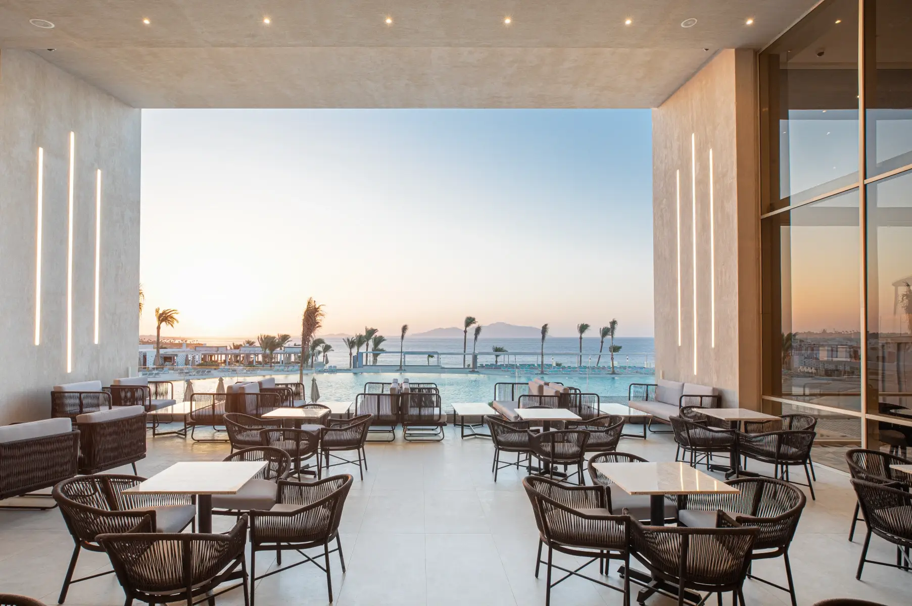 Vie Bar terrace at V Hotel Sharm El Sheikh with woven chairs overlooking the pool and Red Sea at sunset